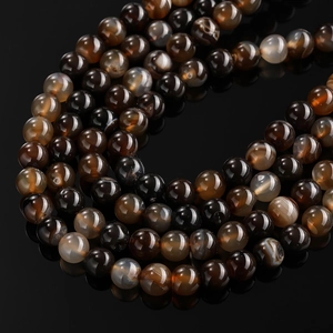 Macro shot of polished dragon vein agate beads with natural banded textures on dark reflective surface