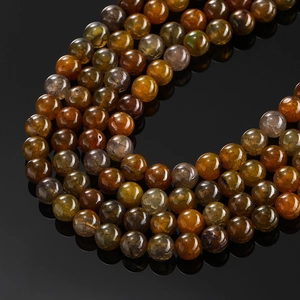 Macro shot of polished dragon vein agate beads with amber and green cracked textures