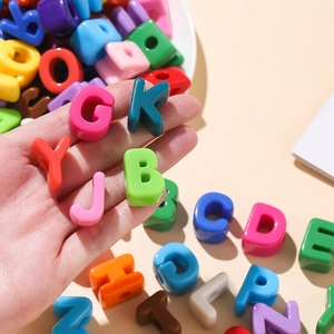 Macro shot of colorful acrylic alphabet beads held in hand for DIY jewelry making