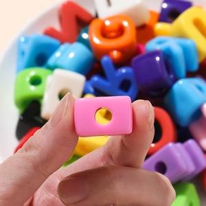 Close-up of a pink acrylic letter bead showing the center hole for DIY jewelry making