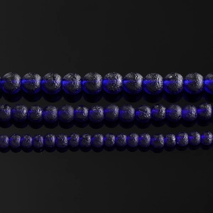 Macro view of black lava stone beads with fluorescent blue centers for jewelry making