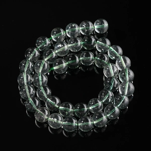 Macro shot of green thread through polished clear crystal beads on black background