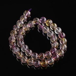 Macro shot of natural ametrine round beads with purple and yellow hues on black background
