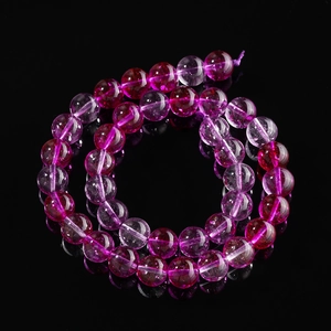 Macro shot of purple phantom glass beads with internal ice crack texture on black mirror