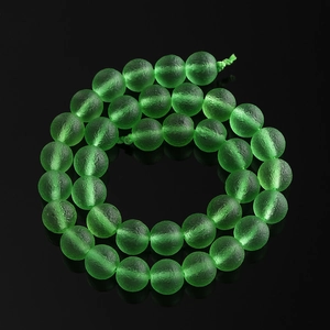 Macro shot of green frosted glass beads with matte texture on black reflective surface