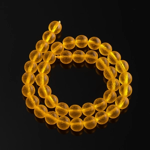 Macro shot of translucent amber round beads with fine textured finish on black background