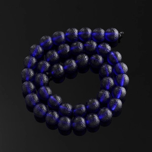Macro detail of dark blue frosted moldavite glass beads with crater texture for DIY jewelry