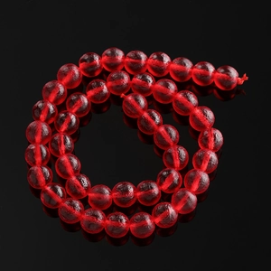 Macro shot of red translucent Czech glass beads spirally arranged on black mirror