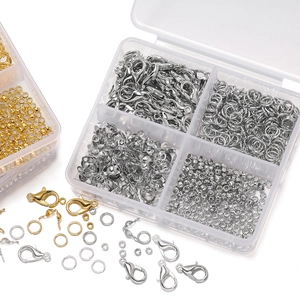 Macro view of gold and silver lobster clasps and jump rings in a clear organizer box
