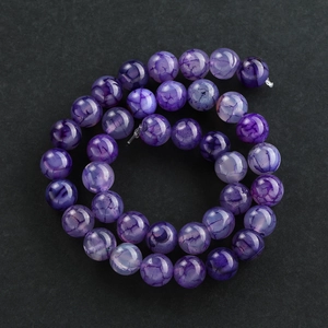 Macro-opname van paarse agaatkralen met natuurlijke drakennerfstructuur voor DIY-sieraden