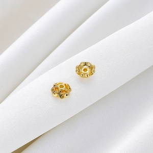Makroaufnahme der 18K vergoldeten Perlenkappen in Blumenform für DIY-Schmuck auf Seide