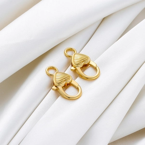 Dettaglio dei fermagli a moschettone a cuore placcati oro 14K su raso bianco lucido