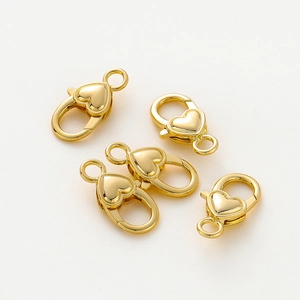 Dettaglio di quattro chiusure a moschettone a cuore placcate oro 18k per gioielli fai da te