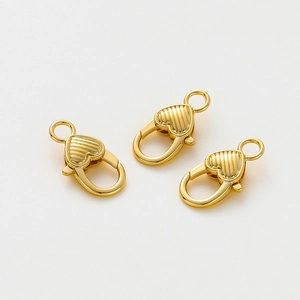 Dettaglio di moschettoni a cuore placcati oro 14K con linee verticali testurizzate