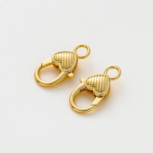 Dettaglio di chiusure a moschettone a cuore in oro 14K con texture a strisce verticali e molla
