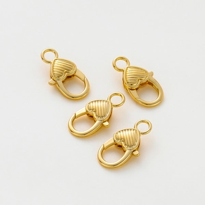 Dettaglio di quattro chiusure a moschettone a cuore placcate oro 14K con rilievo a righe