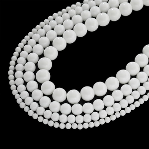 Close-up of white ceramic beads in multiple sizes arranged on a dark background