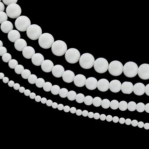 Detail showing four sizes of smooth white ceramic round beads for DIY jewelry making