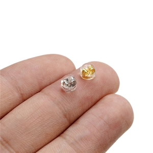 Macro shot of silicone earring backs with gold and silver cores on a finger tip