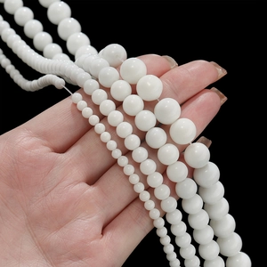 Macro shot of various sizes of white ceramic beads held by hand for DIY jewelry making
