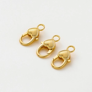 Dettaglio macro di chiusure a moschettone a cuore placcate oro 14K con texture a righe