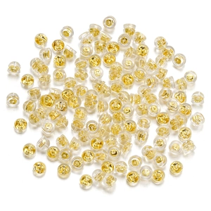 Close-up of golden metal butterfly backs and transparent silicone earring stoppers
