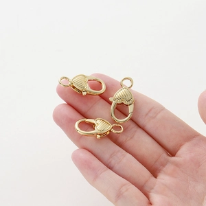 Tre chiusure a moschettone a cuore placcate oro 14K per gioielli viste su mano