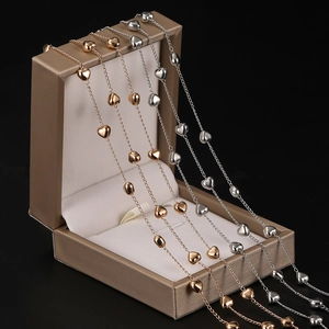 Detalle de dijes de corazón pulido en collares de cadena de cobre en color oro y plata