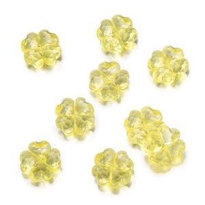 Detalle macro de ocho cuentas de trébol de acrílico facetado amarillo para joyas DIY