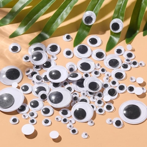 Assorted sizes of self-adhesive googly eyes for DIY crafts on a warm orange surface