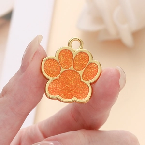 Gros plan d'un pendentif patte de chien doré avec émail orange scintillant et paillettes