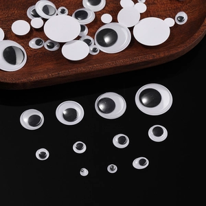 Macro shot of assorted googly eyes in various sizes on wood and black background