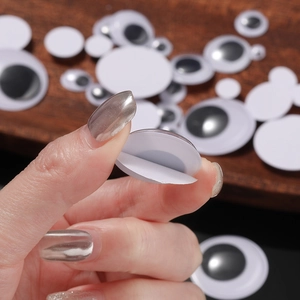 Self-adhesive googly eyes for DIY crafts in various sizes on a wooden background