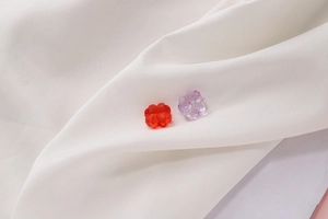 Detalle macro de cuentas de trébol en acrílico rojo y morado para bisutería artesanal