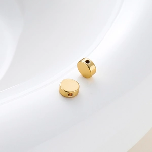 Close-up of polished 18K gold-plated flat round spacer beads with precision holes