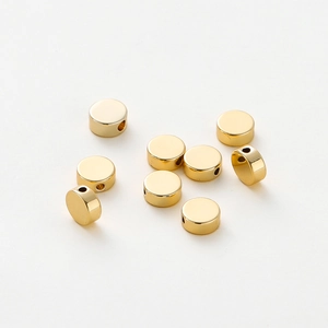Detailed view of nine polished gold-plated flat round spacer beads for jewelry making
