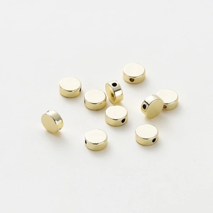 Close-up of polished gold-plated flat round spacer beads with side holes for DIY jewelry