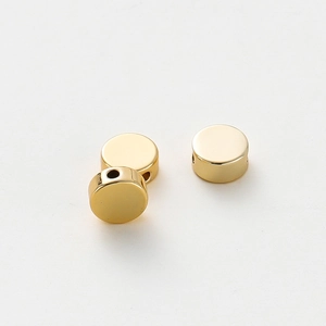 Detailed close-up of three polished gold-plated flat round spacer beads for jewelry DIY