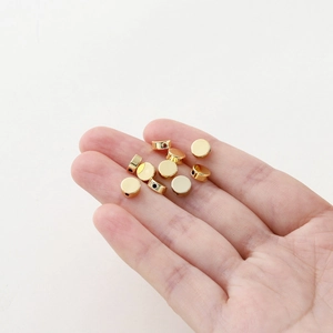 Golden plated 14K gold flat round spacer beads for DIY jewelry making displayed on hand