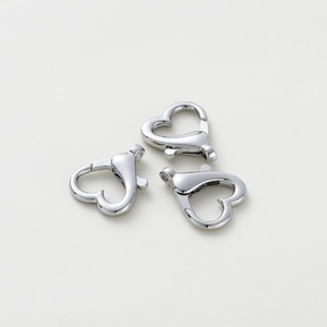 Dettaglio di tre chiusure a moschettone a forma di cuore argento per gioielli fai-da-te