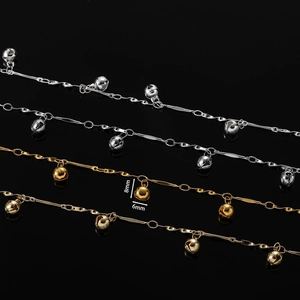 Détail de chaînes de cœur or et argent avec cloches de 8mm sur fond noir réfléchissant