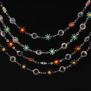 Macro detail of colorful enamel daisy charms and faceted crystals on jewelry chain