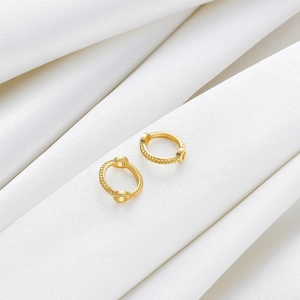 Detalle de aretes huggie de cuentas chapados en oro de 18K con textura de cuerda en seda