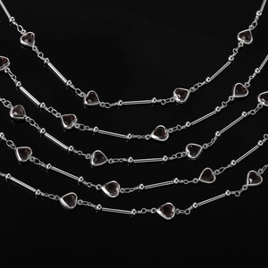 Détail macro de la chaîne cœur plaquée argent avec pendentifs en cristal rouge sur noir