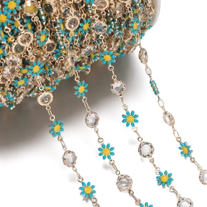 Macro detail of daisy flower and crystal bead chain on white plastic spool for DIY jewelry