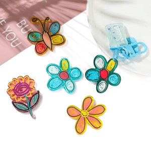 Flat lay of colorful acrylic butterfly and floral charms with Sweet tag for DIY crafts