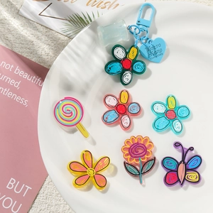 Close-up of colorful acrylic flower and butterfly charms in a white ceramic dish