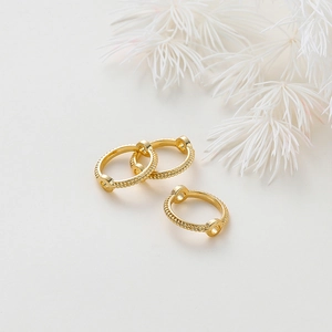 Detalle de anillos de cuentas dorados de 18K con textura trenzada para joyería creativa