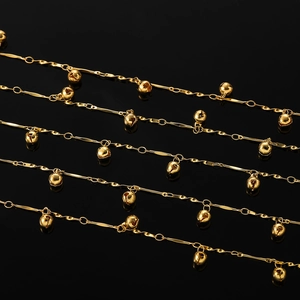 Vue macro de chaînes dorées à cloches avec barres métalliques sur fond noir miroir