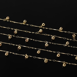 Gros plan sur les maillons dorés à cœurs et clochettes pour bijoux DIY sur fond noir
